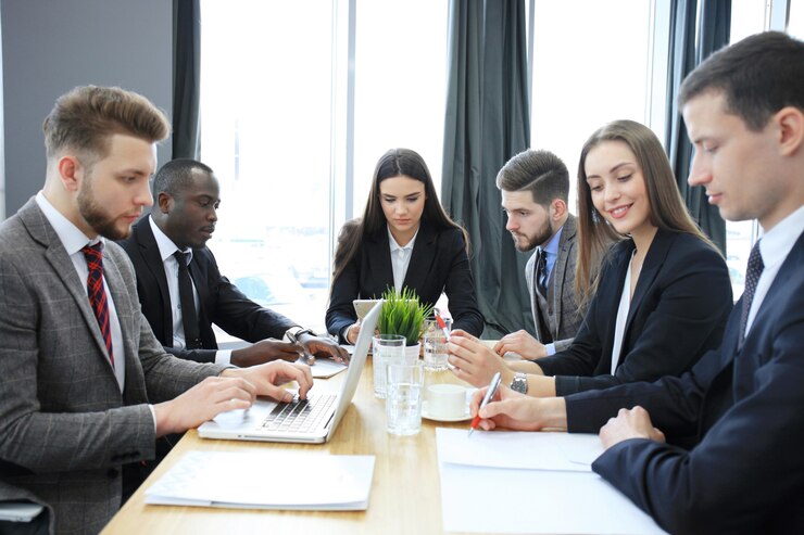 young-handsome-woman-gesturing-discussing-something-while-his-coworkers-listening-him-sitting-office-table_484651-9109